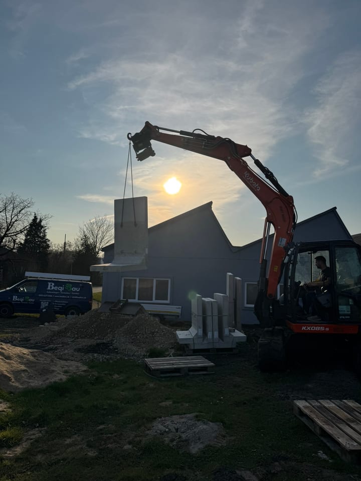 Baggerarbeiten in Bielefeld - Minibagger hebt Betonelement im Abendlicht