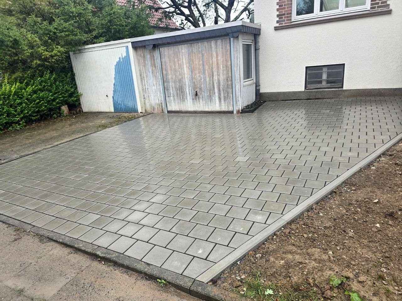 Fertige Einfahrt aus grauem Betonpflaster vor einer Garage