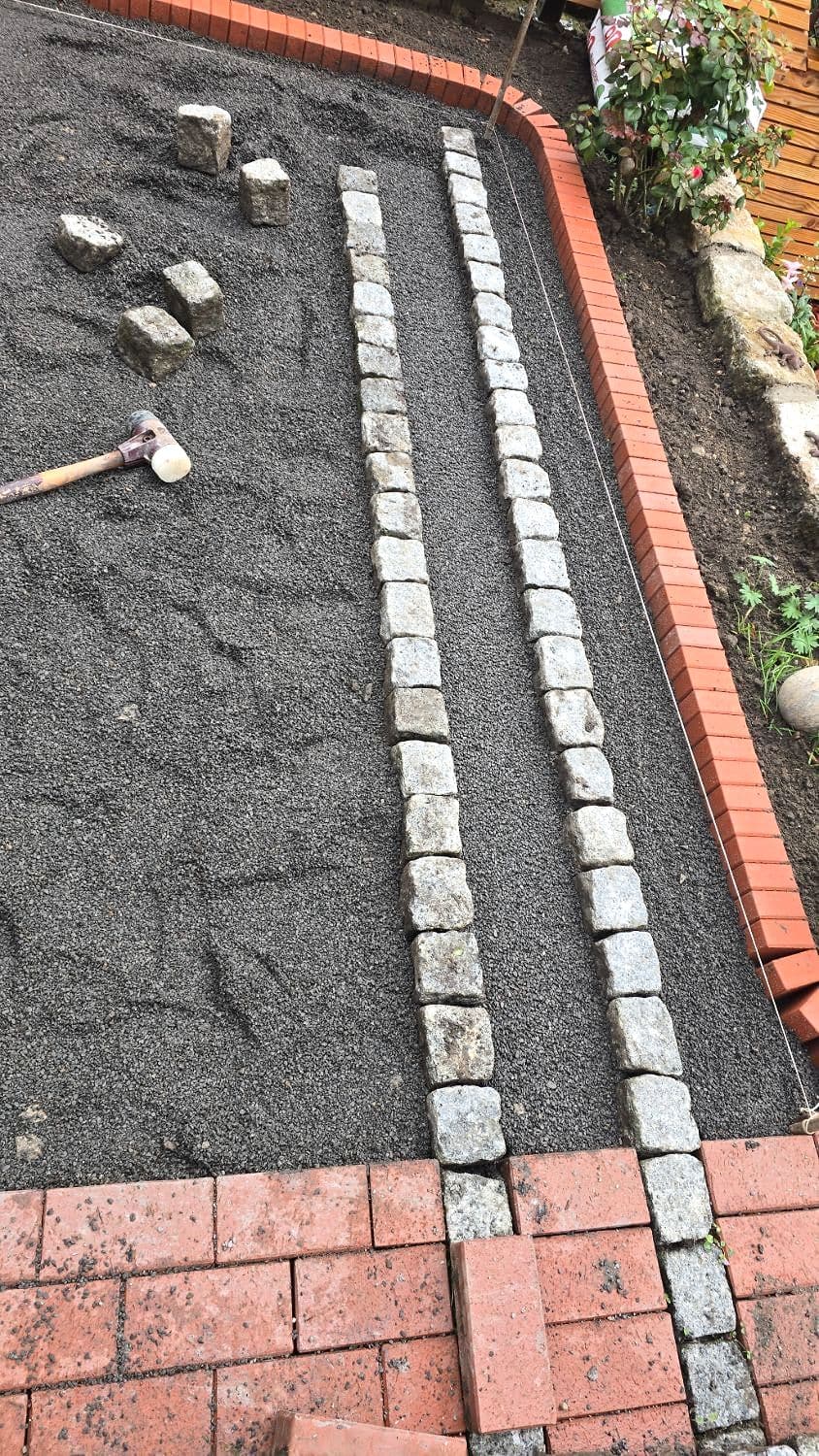 Auf dem abgezogenen Splittbett werden zuerst die doppelten Granitbänder nach Schnur gesetzt