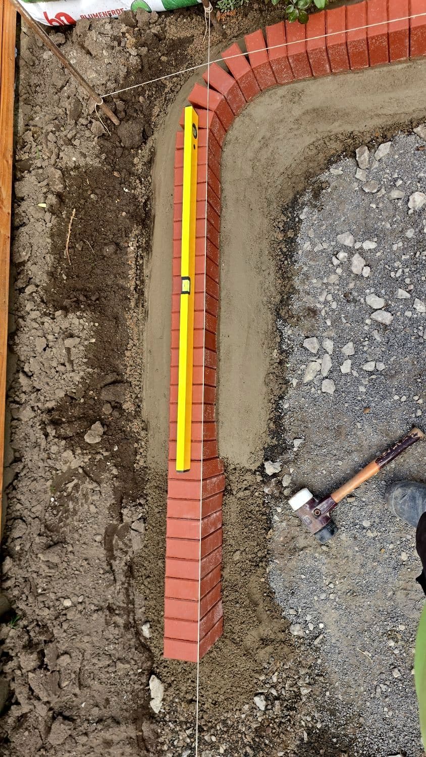Die Rollschicht wird nach Schnur und Wasserwaage gesetzt, an der Ecke im Bogen